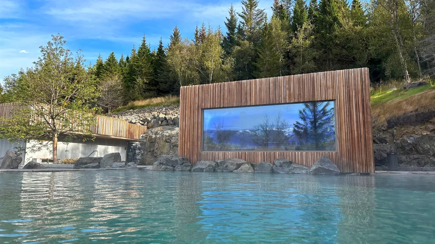 Blue and pine interiors of the Kingfisher Lodge glamping tent, including a couch, glass coffee table, double bed and bookshelves.