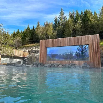 Blue and pine interiors of the Kingfisher Lodge glamping tent, including a couch, glass coffee table, double bed and bookshelves.