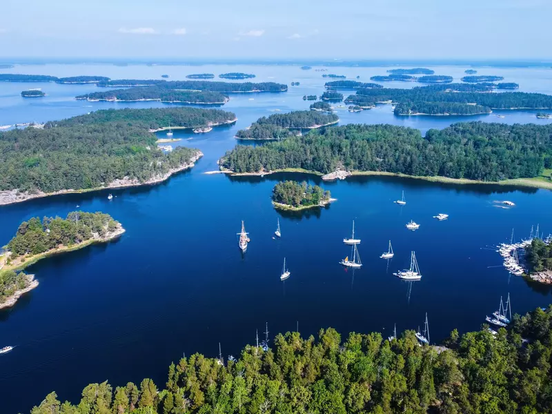 Boats in blue water with many green islands.