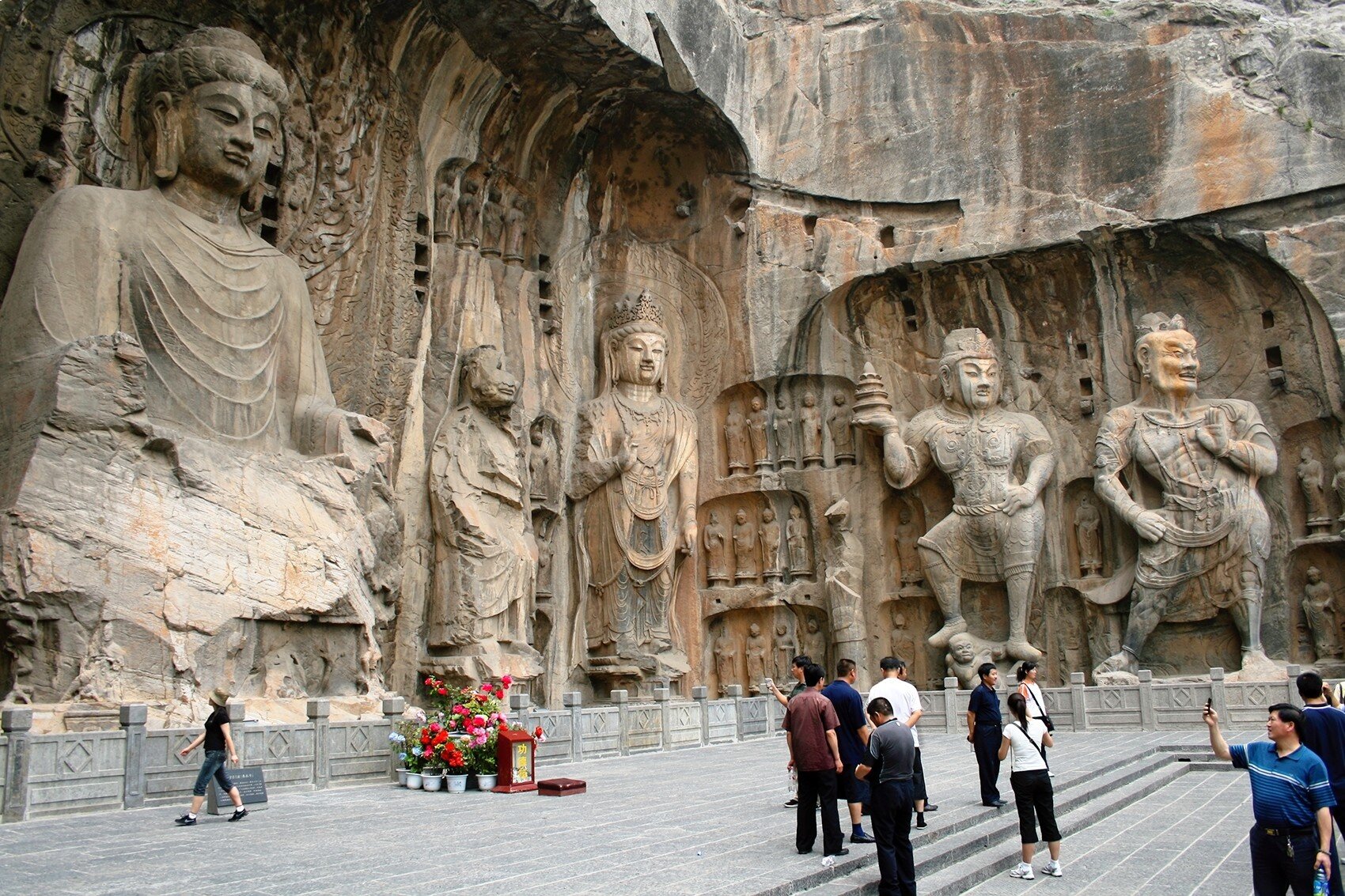 Luoyang, China - June 19, 2008: Tourists take photos in front of the massive stone carvings of Buddha at the Longmen Grottoes.