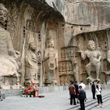 Luoyang, China - June 19, 2008: Tourists take photos in front of the massive stone carvings of Buddha at the Longmen Grottoes.