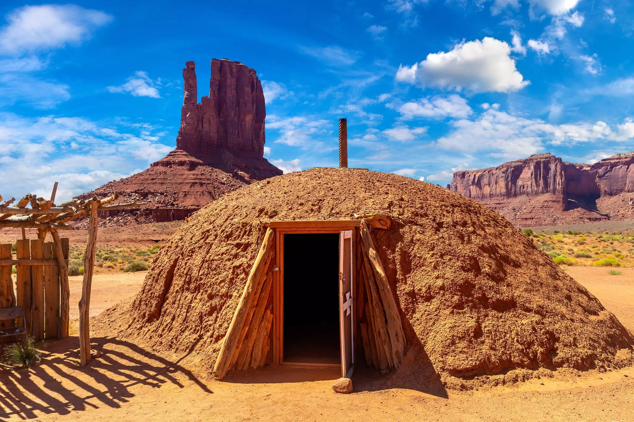 A hexagonal hut made of earth with a wooden doorway