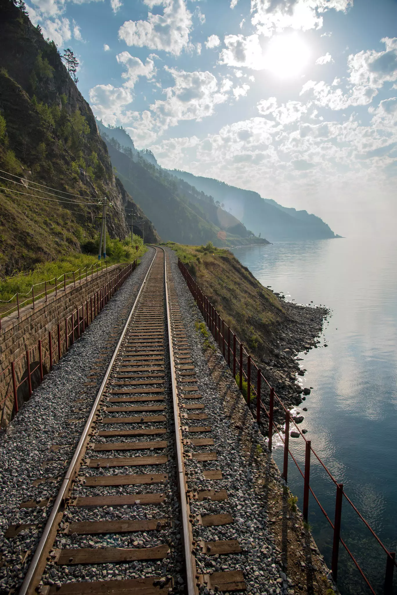Snow-covered train tracks with a blue-and-red train approaching