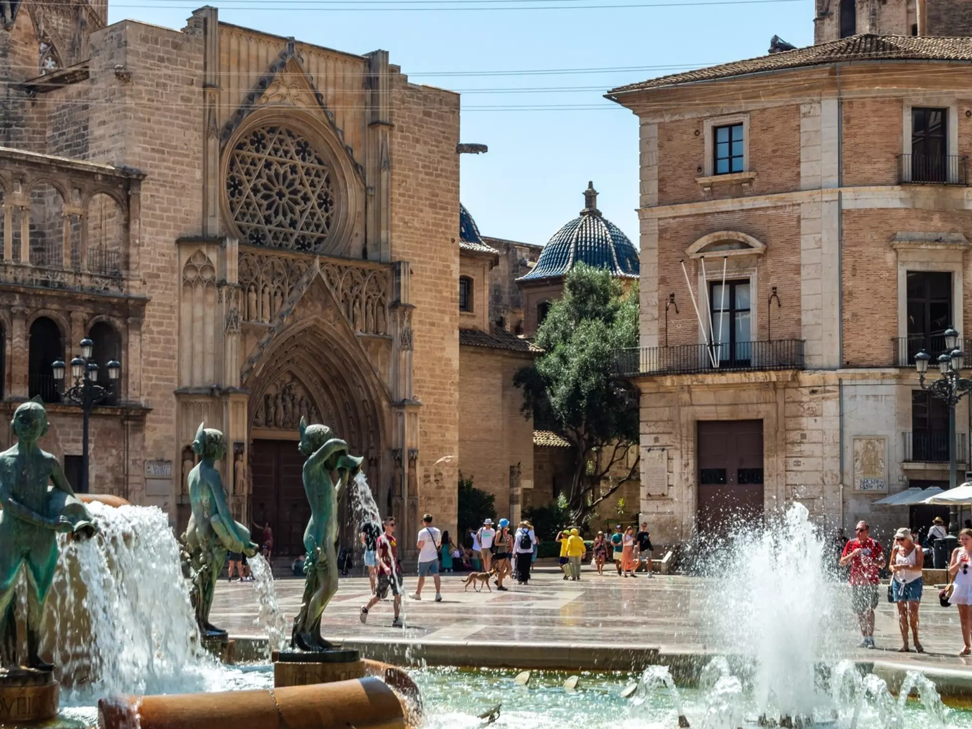 Water jets of the Fountain of the Turia play before the Gothic portal of Valencia Cathedral and the blue-tiled dome of the basilica.
