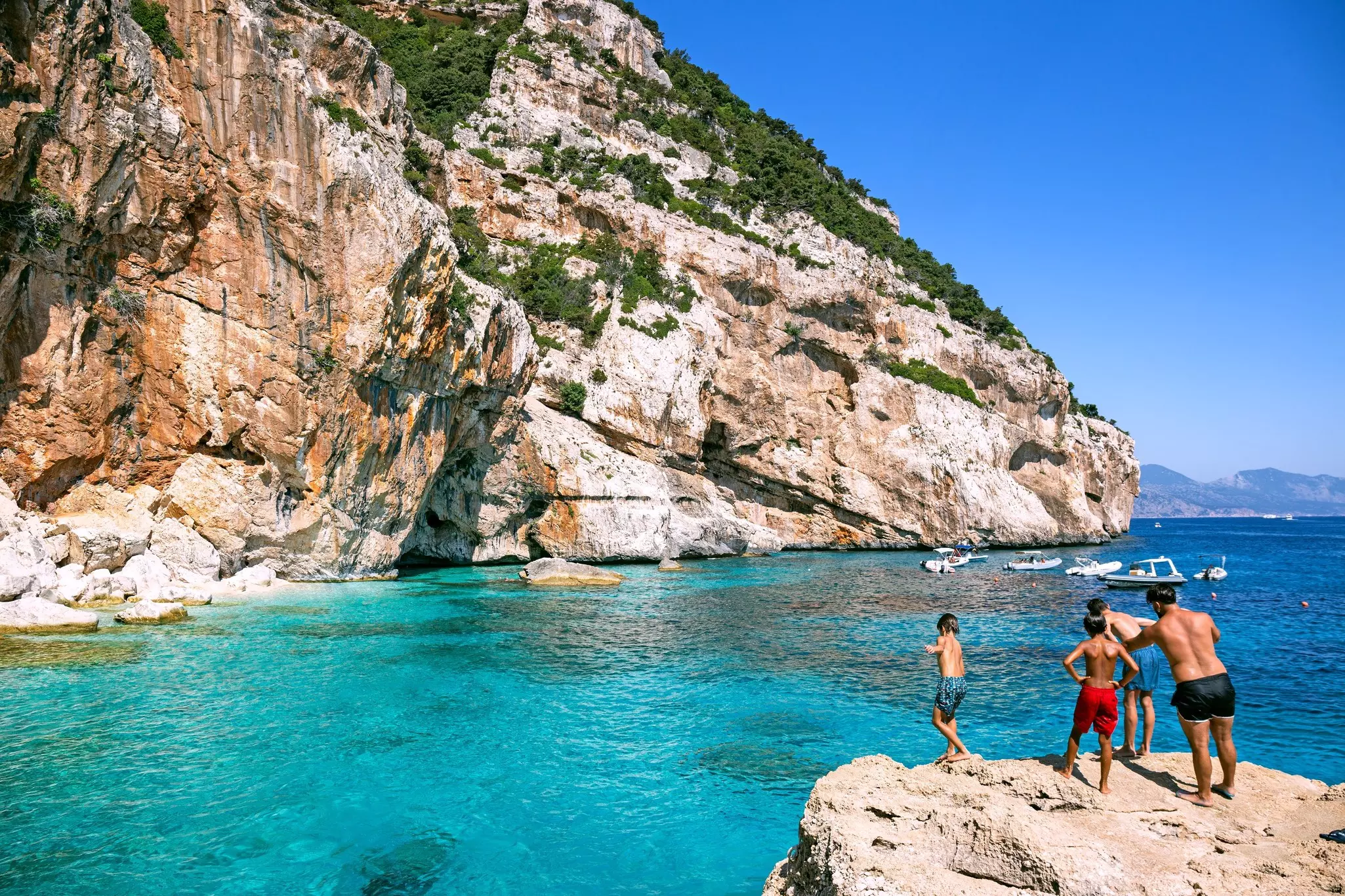 People jumping from the cliff into turquoise waters of Cala Mariolu, Sardinia