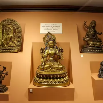 Nepal, Lalitpur - May 10, 2019: Group of bronze Buddha and Hindu Gods figurines on orange background in showcase of Patan Museum on Patan Durbar Square. Soft focus. Religious heritage theme.; Shutterstock ID 2273076965;