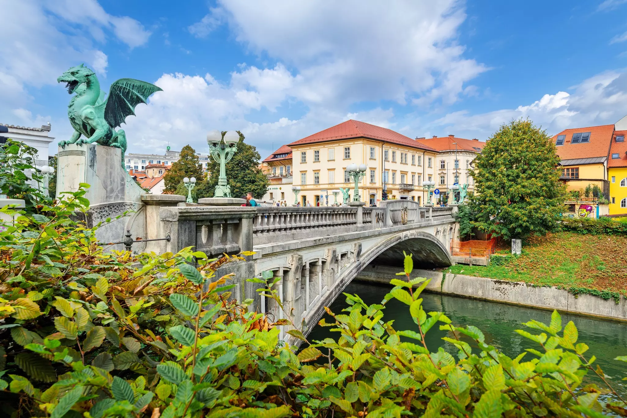 A bridge with a dragon sculpture over a river.