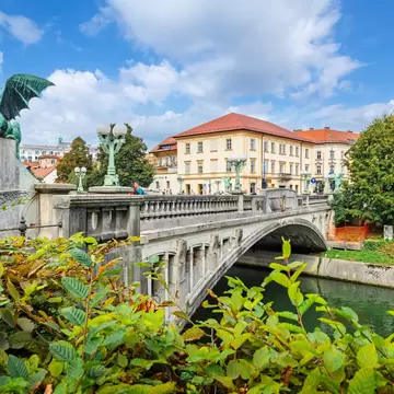A bridge with a dragon sculpture over a river.