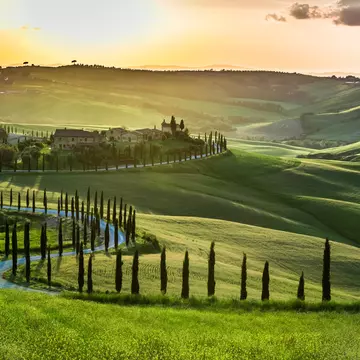 Sunset over the winding road with cypresses in Tuscany.