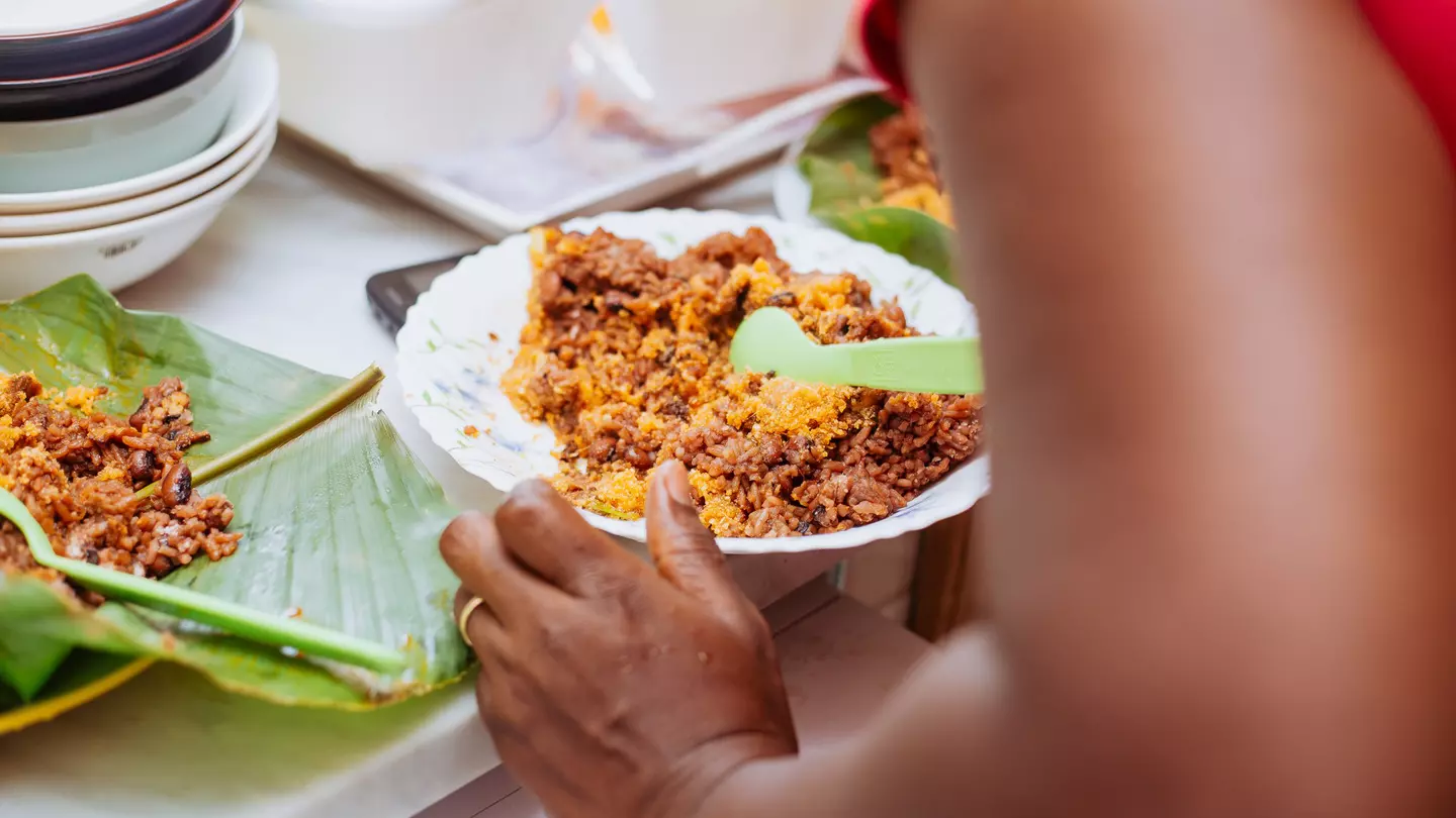 Cropped hands of woman having a plate of jollof rice at a table