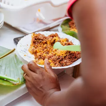 Cropped hands of woman having a plate of jollof rice at a table