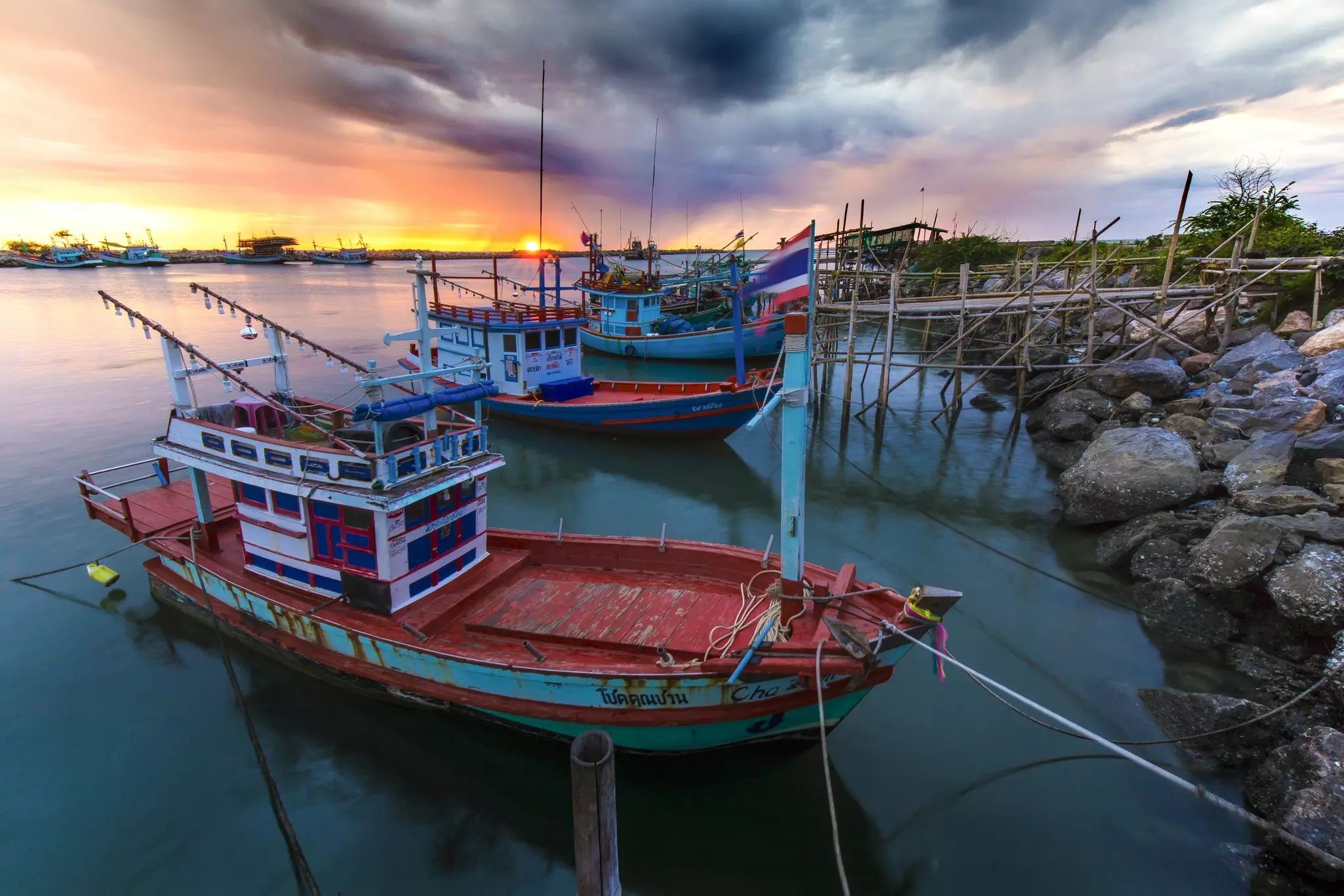 Colorful fishing boats docked on a rocky coastline at sunset