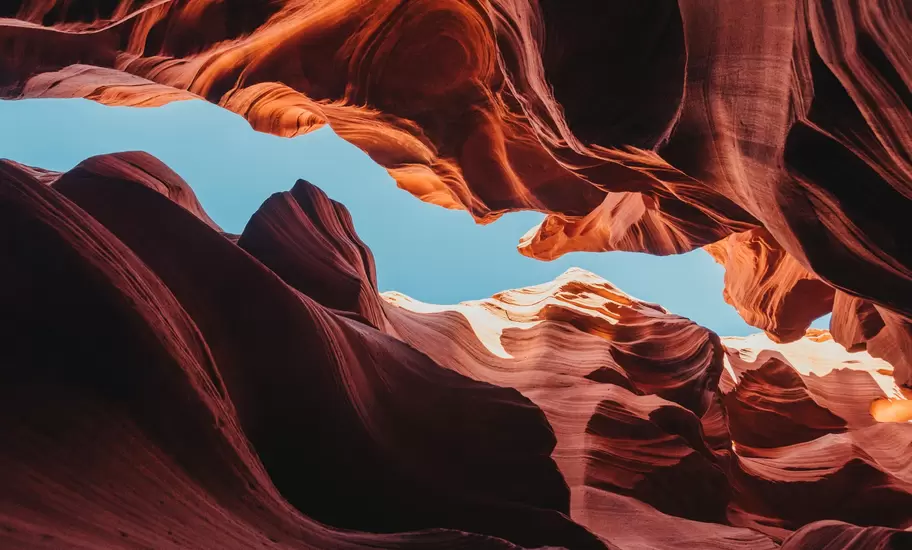 Antelope Canyon-style slot canyon in Arizona, with red and orange sandstone walls curving around a strip of blue sky