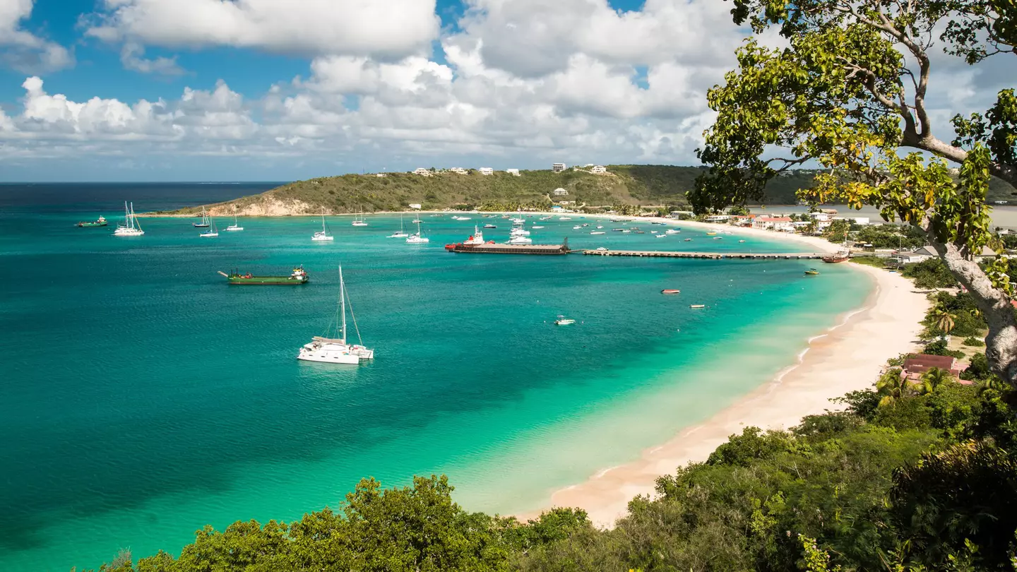 Boats in a turquoise ocean by a sandy beach.