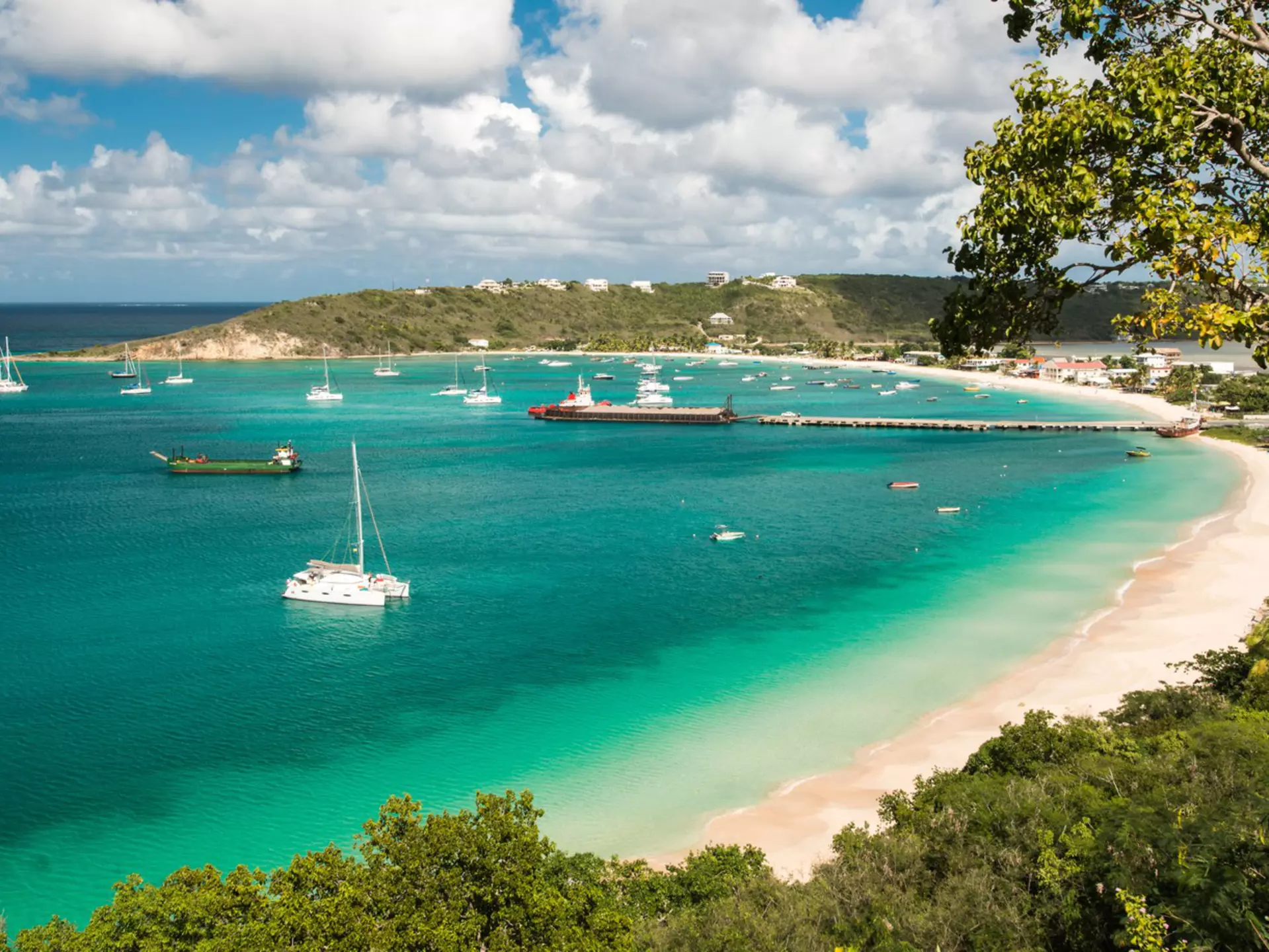 Boats in a turquoise ocean by a sandy beach.