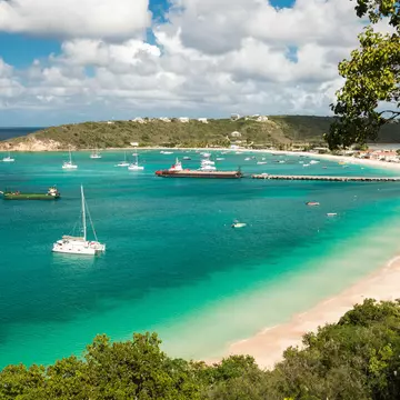 Boats in a turquoise ocean by a sandy beach.