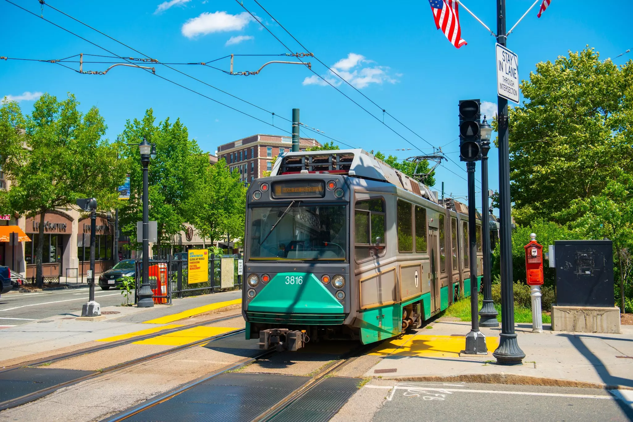 A green light rail train adjacent to a city street