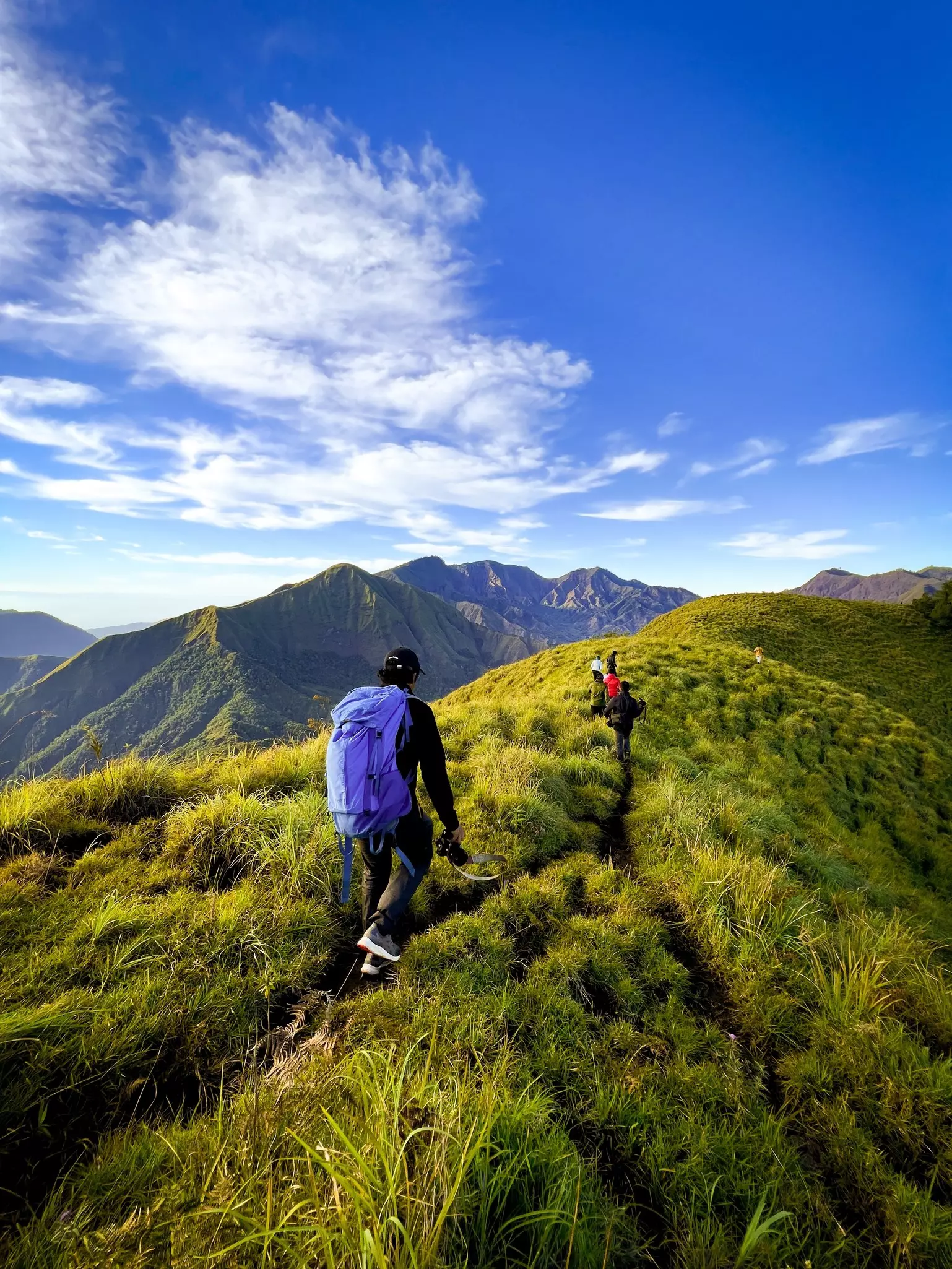 People hiking up a mountain, with other mountains nearby