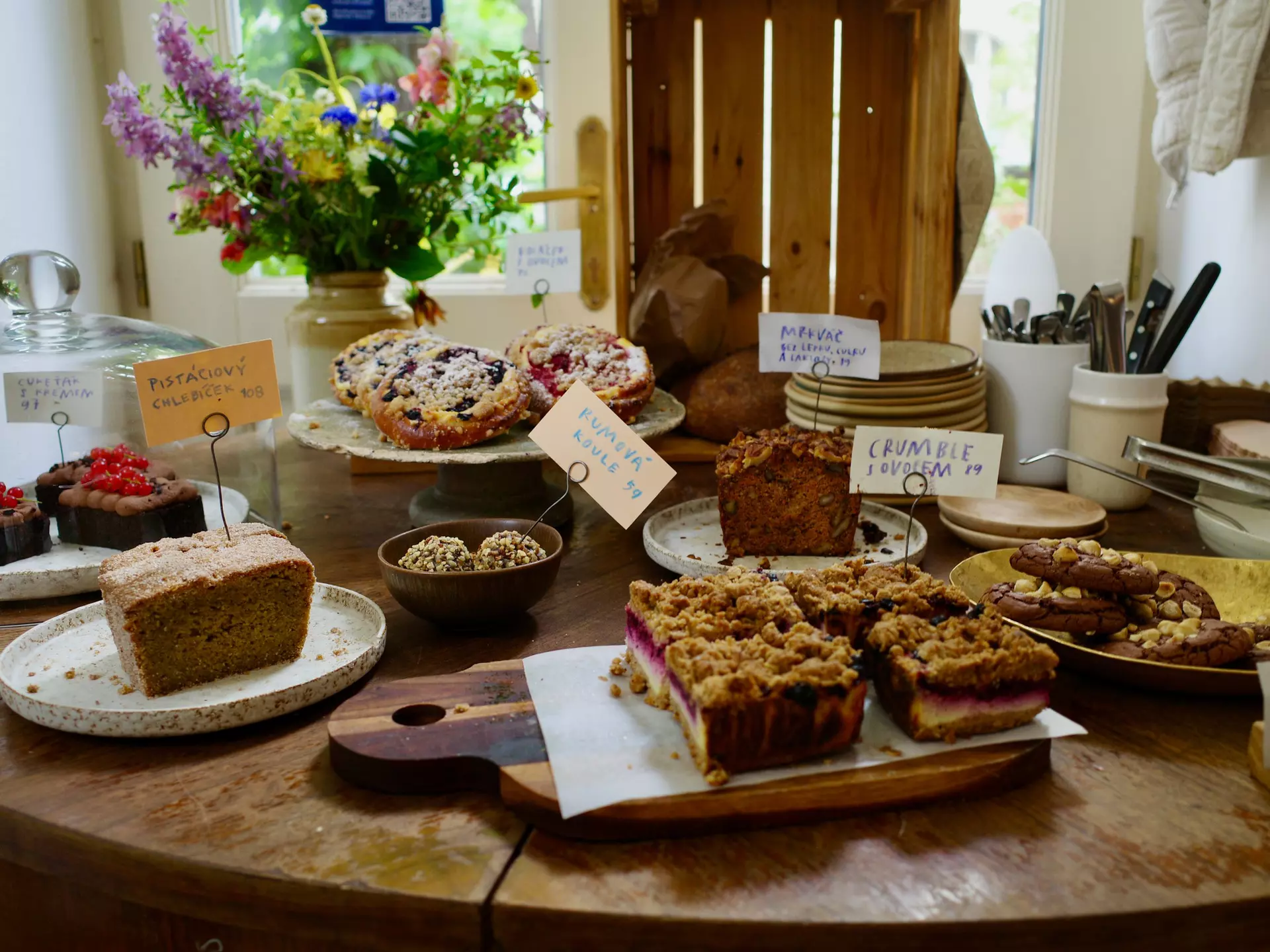 A variety of baked goods on display on a wood table, with tags identifying each 