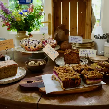 A variety of baked goods on display on a wood table, with tags identifying each 