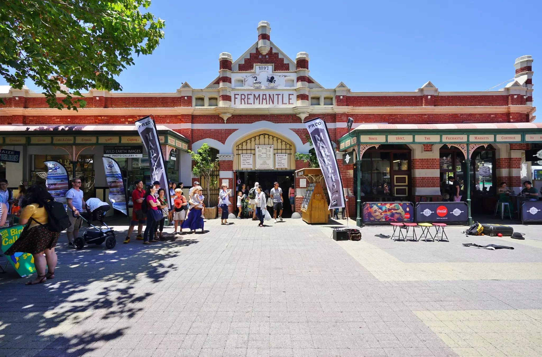 People near the entrance to a large red-brick market building.