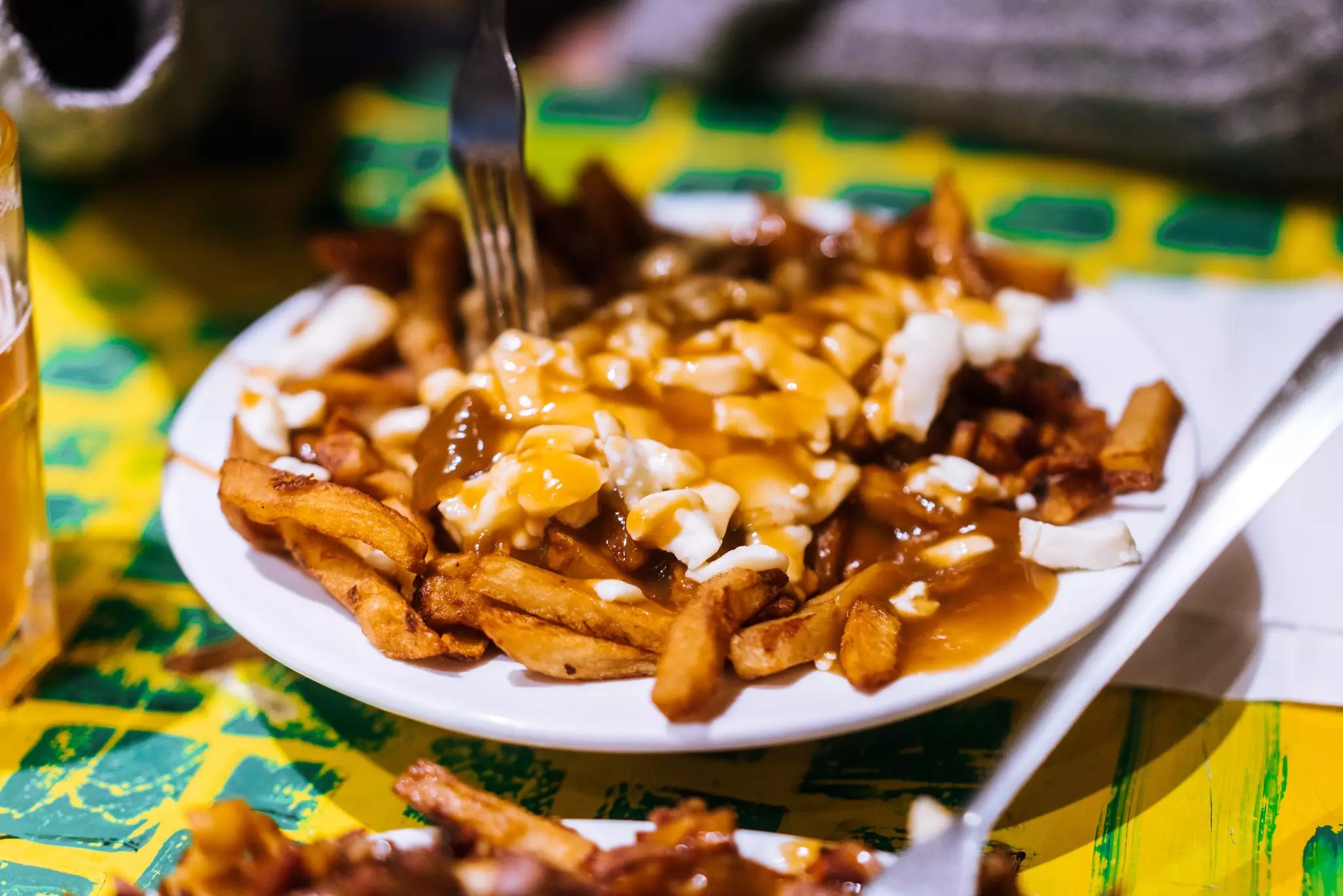 Plate of Montreal poutine with fries gravy and cheese curds on a white plate at a diner