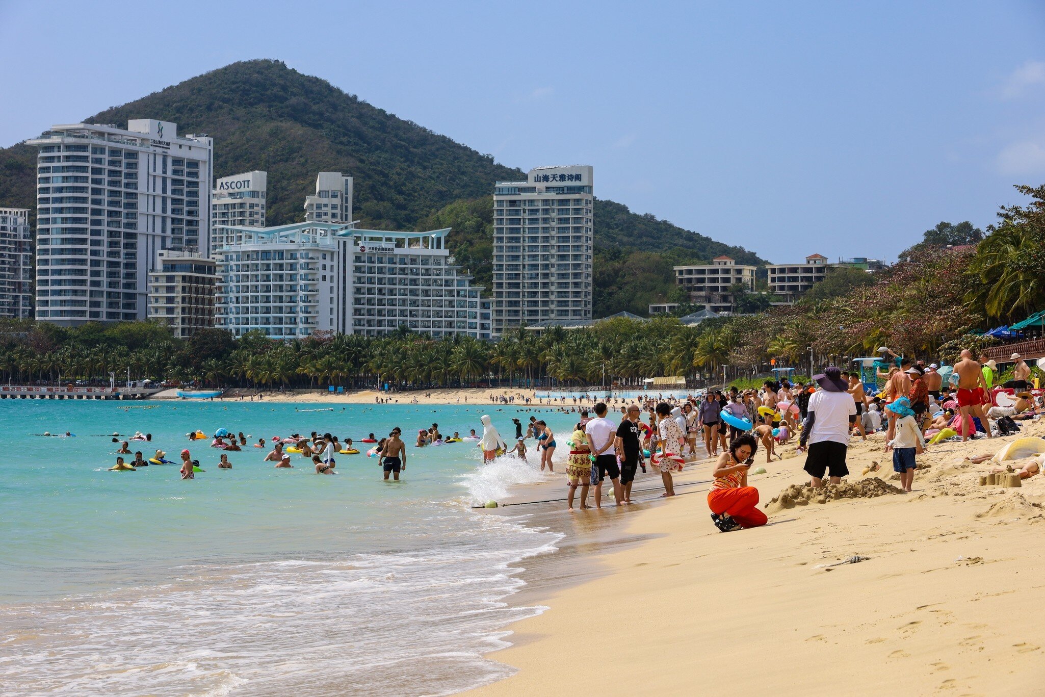 Sanya, China - February 23, 2025: Crowd of people tanning and swimming on sea beach in Dadonghai bay of Hainan island, License Type: media, Download Time: 2026-09-02T16:20:37.000Z, User: LP_NZhan, Editorial: true, purchase_order: 65050 - Digital Destinations and Articles, job: App Content, client: Lonely Planet App, other: Nadine Zhan
