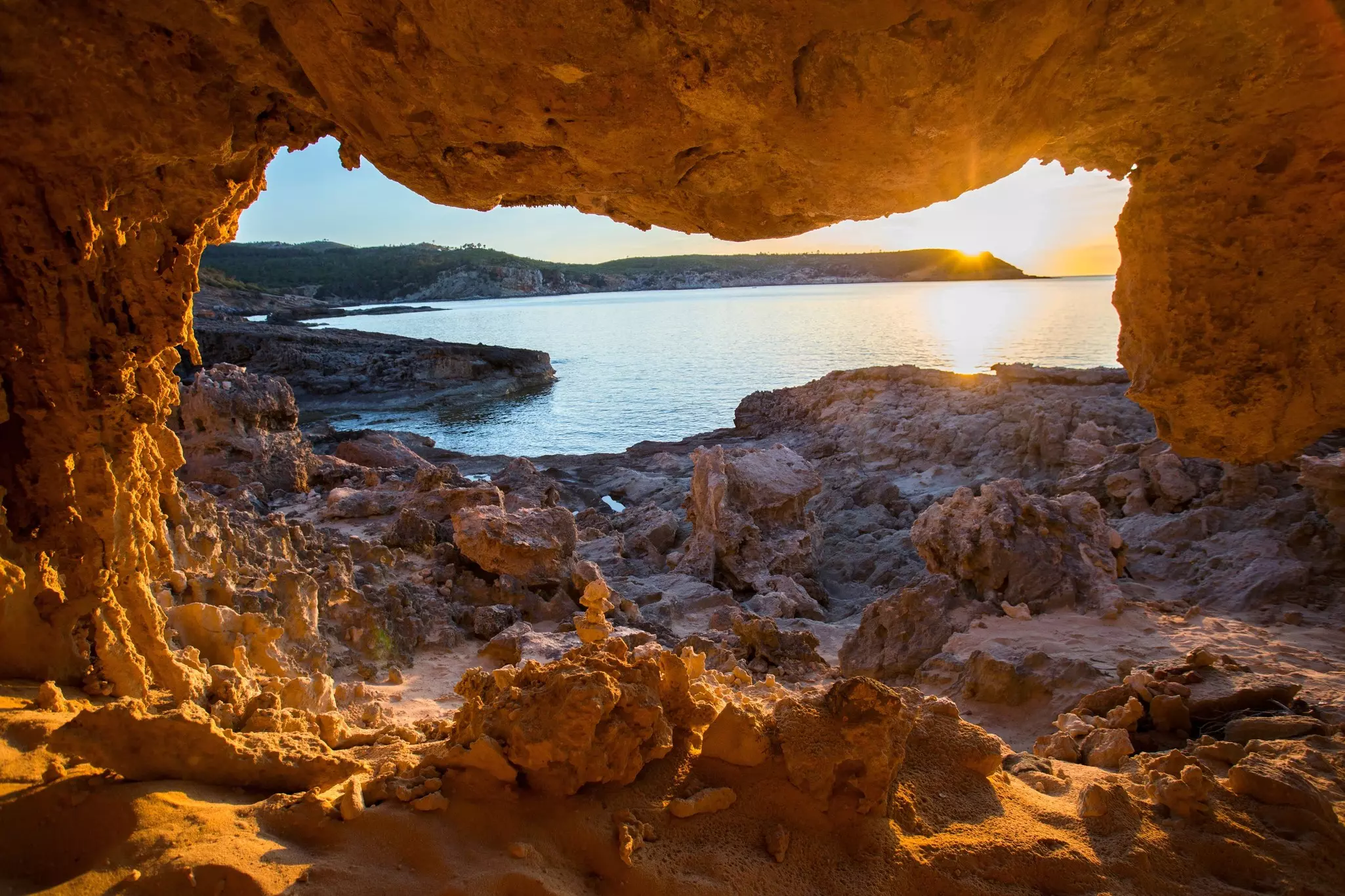 View through a red-rocked landscape onto a beach at sunset