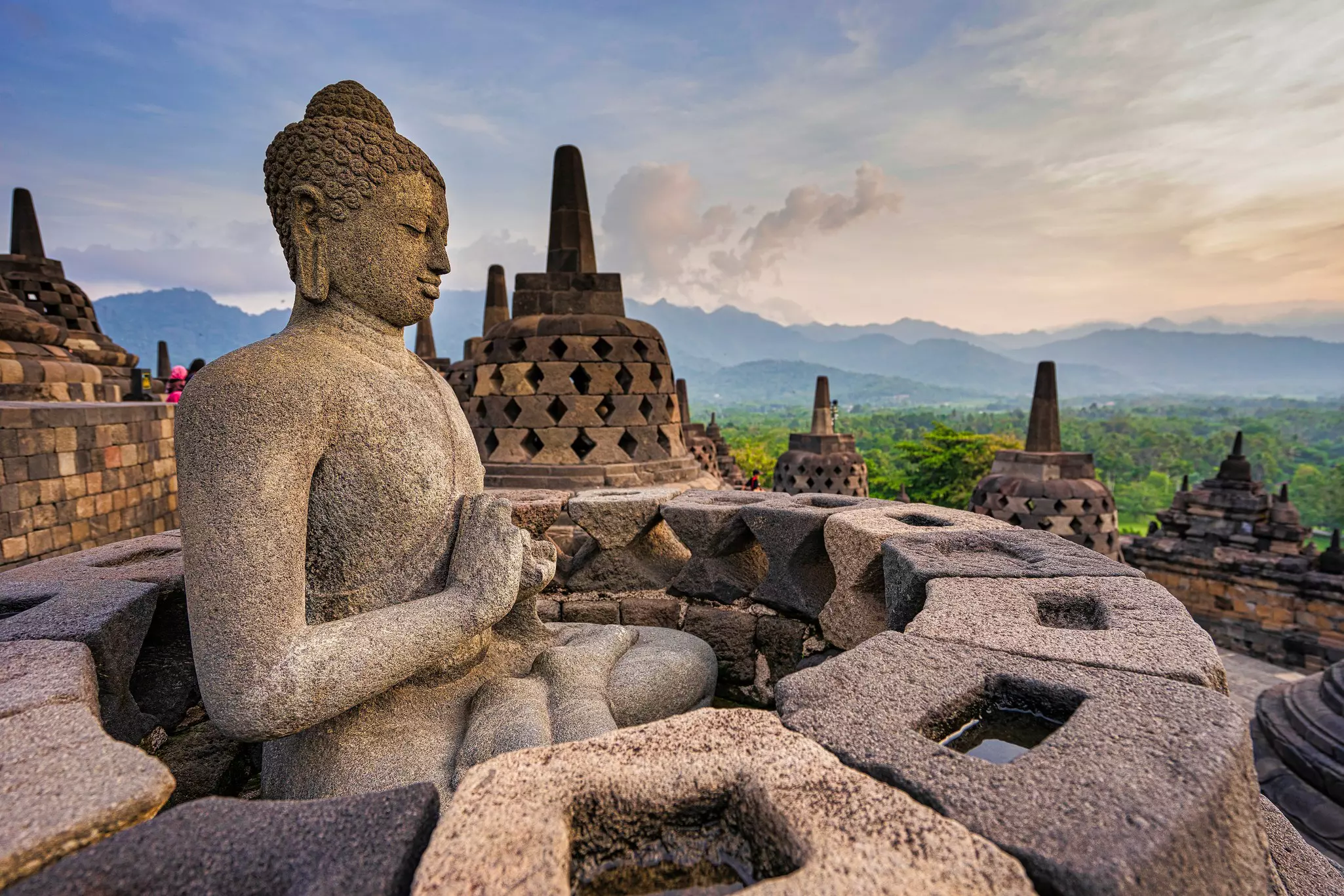 Stone Buddha statue in a small stupa around the top of Borobudur Temple.