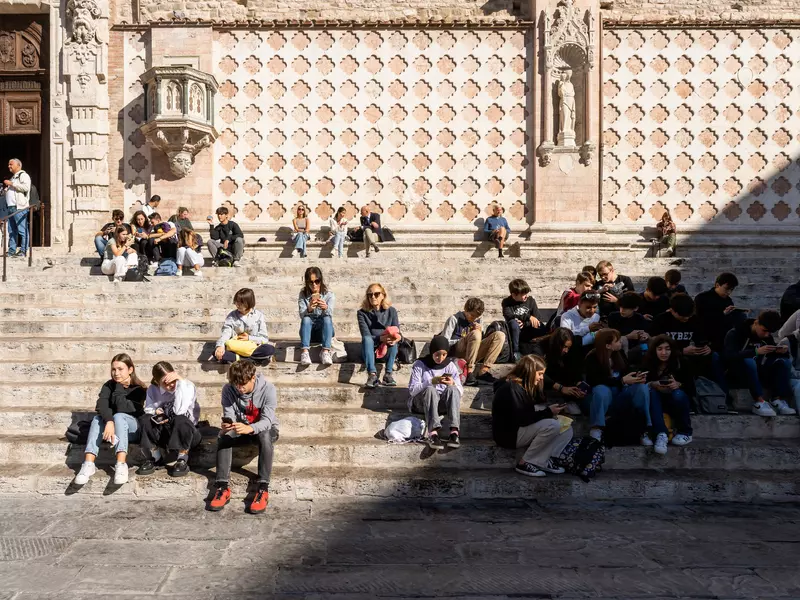 Tourists sit and people-watch on some steps in Piazza IV Novembre