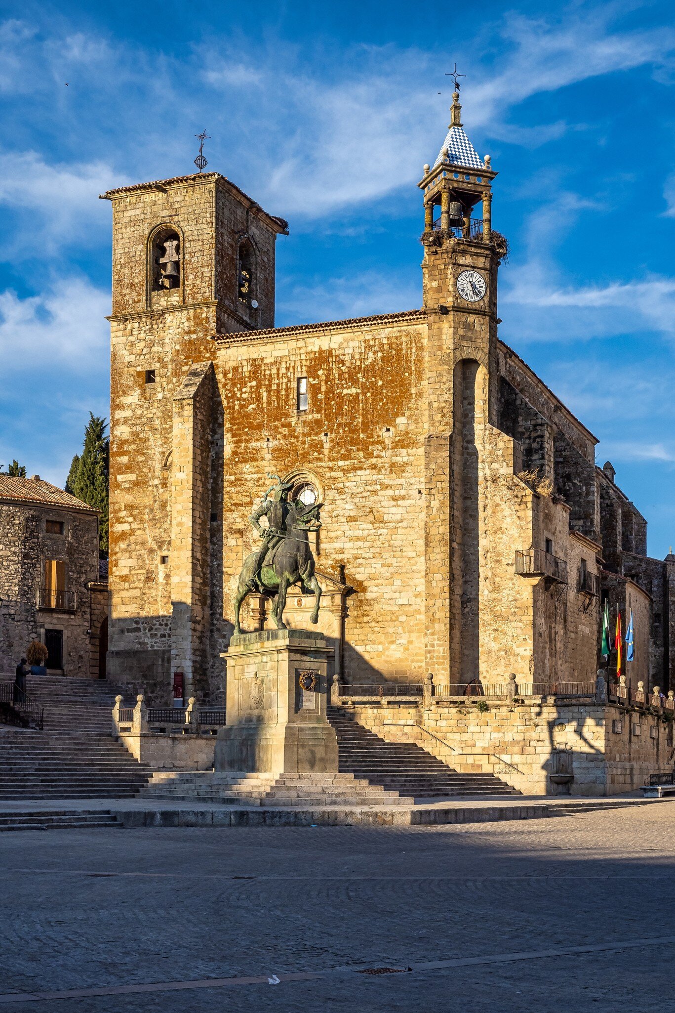 View of a statue and stone church on Plaza Mayor, the main square of Trujillo, Spain.