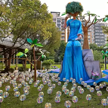 Art installation of a large seated figure in blue in a field of orbs at the Taipei City Hakka Cultural Park.