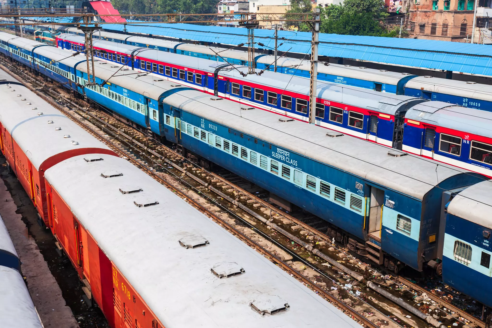 Coaches of four different trains standing in sidings at a major rail hub. One has "Sleeper Class" written on it in large letters.