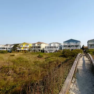 Beach houses across the green sand dunes with a long wooden walkway, Sunset Beach, North Carolina