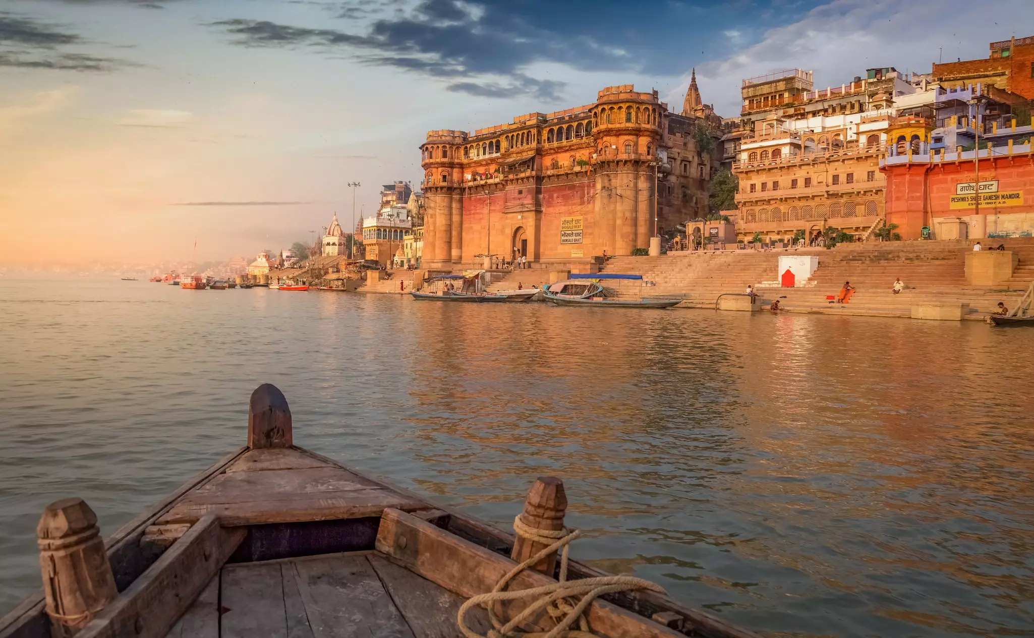 Ghats on the banks of the Ganges during sunset, as seen from a small boat on the river..