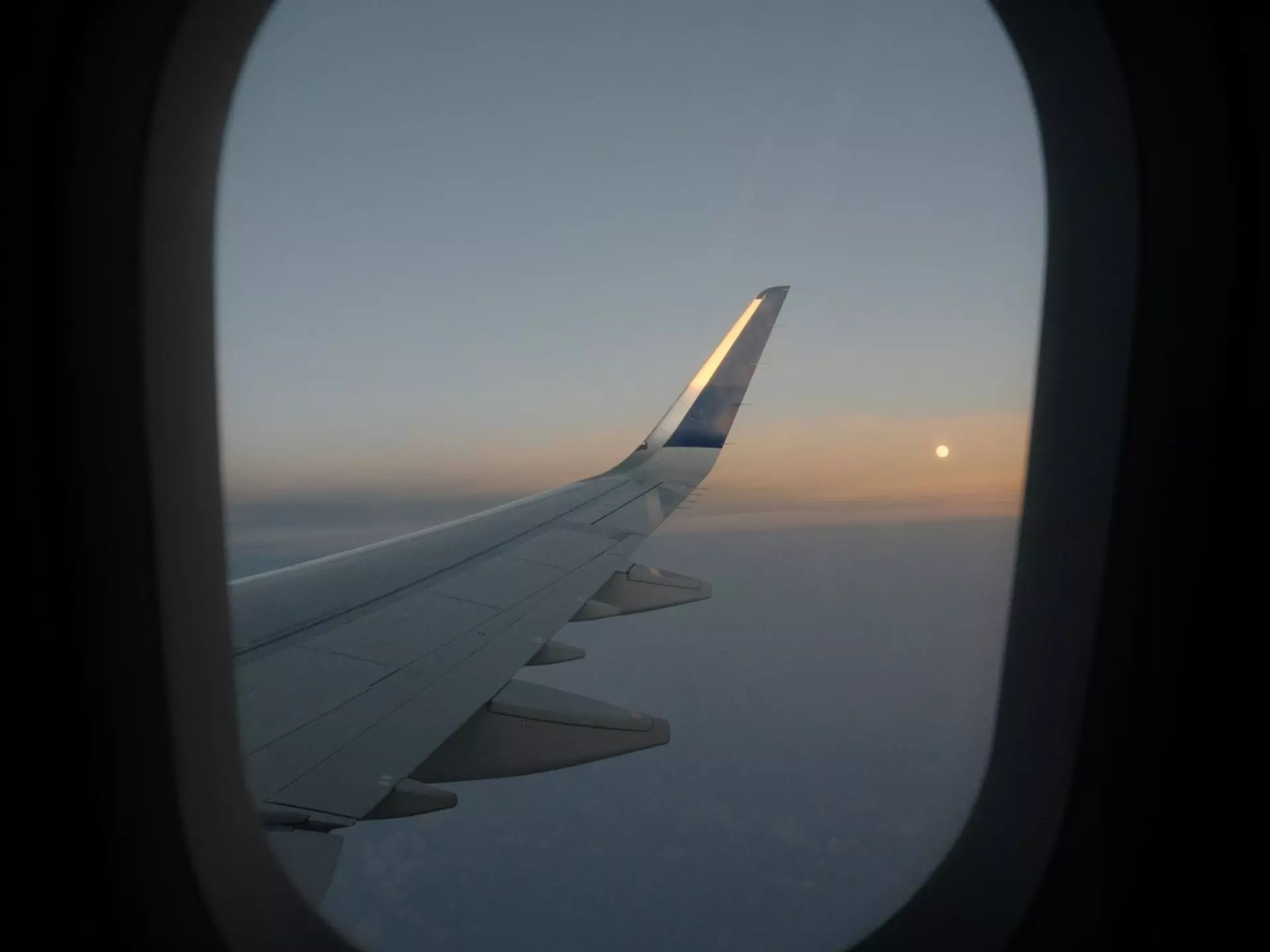 Framed by the window a sunset shot of the plane wing from a flight from Costa Rica to NYC, taken over the Atlantic Ocean on the US East Coast