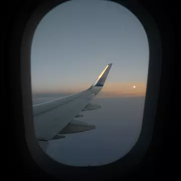 Framed by the window a sunset shot of the plane wing from a flight from Costa Rica to NYC, taken over the Atlantic Ocean on the US East Coast