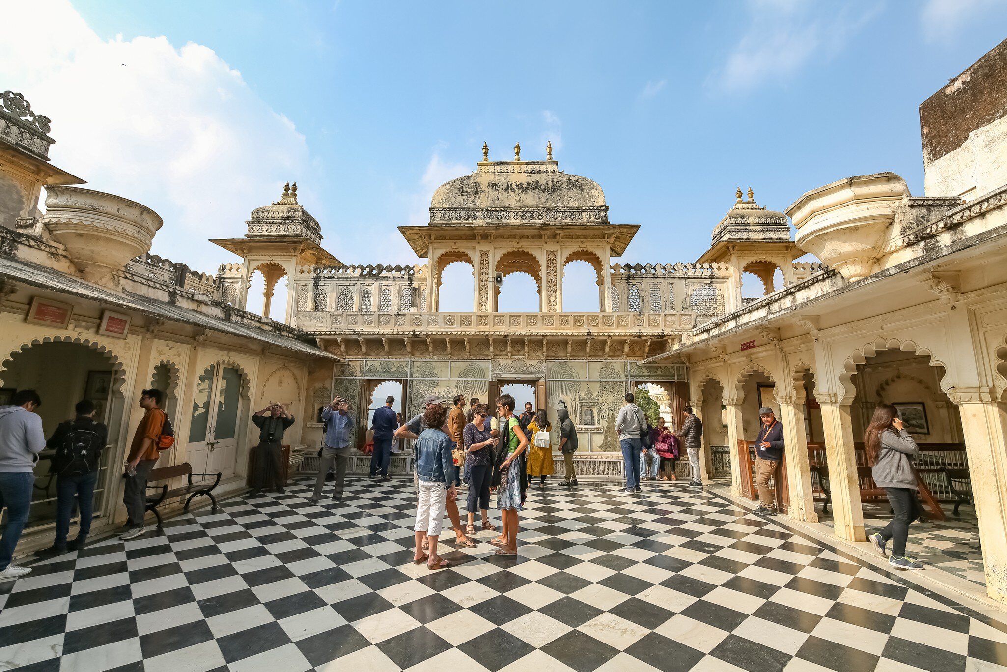 Tourists sightseeing Udaipur City Palace medieval architecture structure built in the year 1553 in Rajasthan, India.