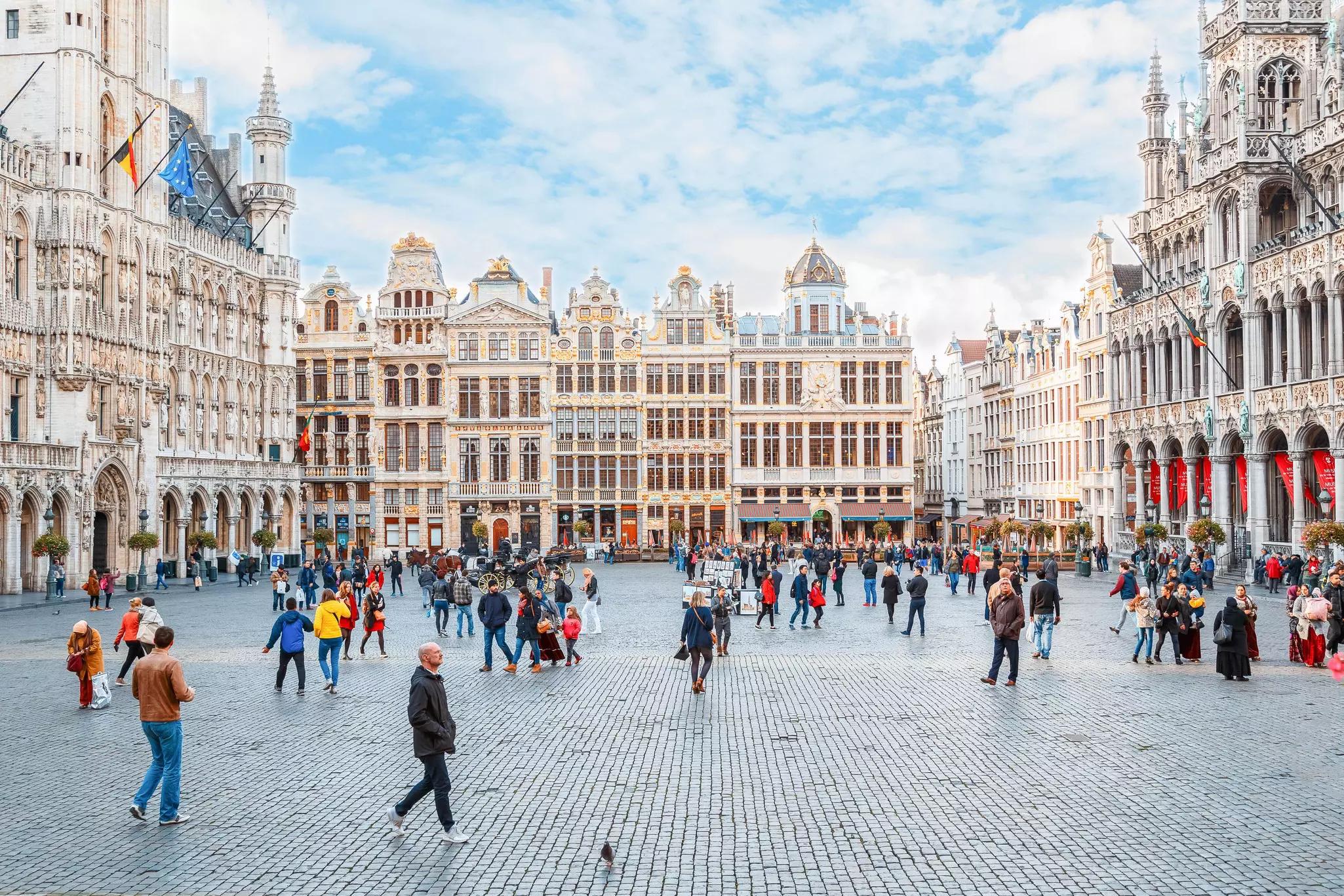 People walking around Grand Place in Brussels, Belgium on a sunny day. 
