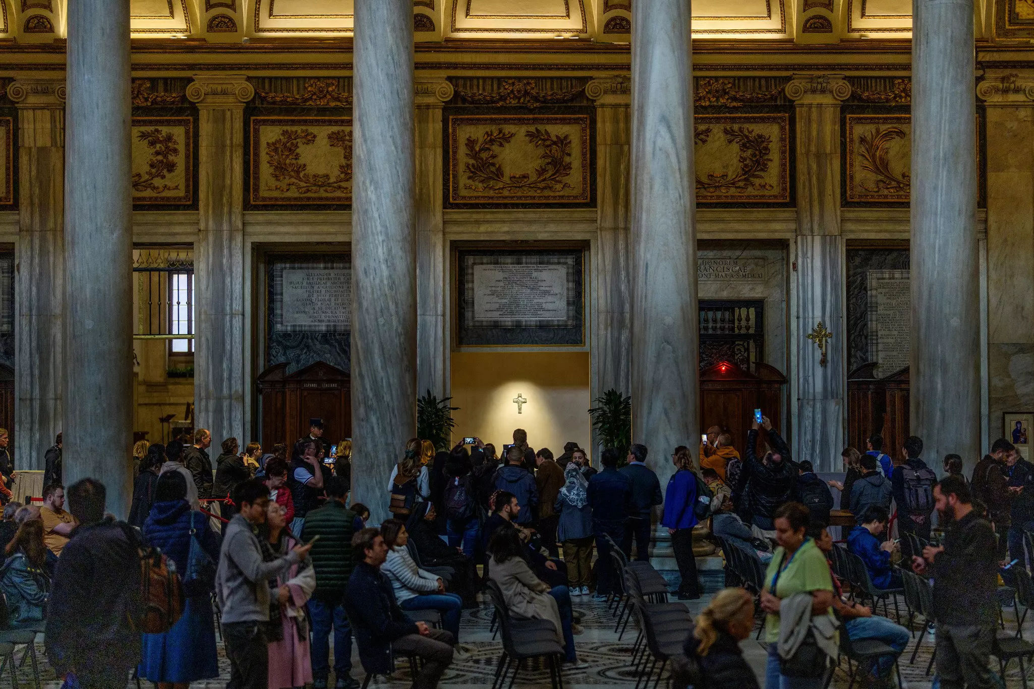 People take photos in a crowded and dimly lit church