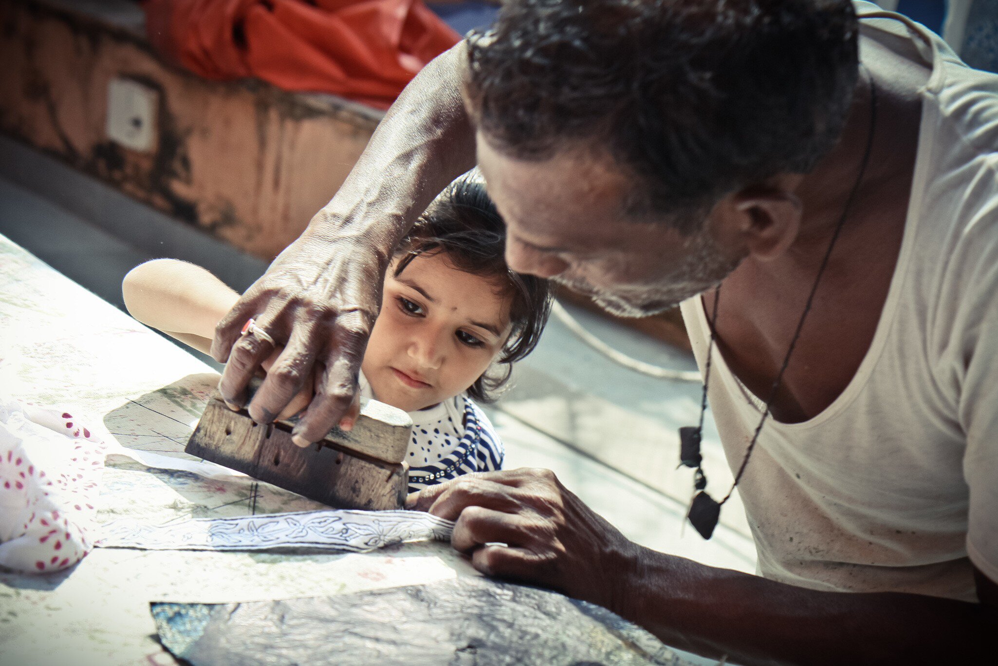 A man at the Anokhi Museum of Hand Printing demonstrates block printing to a young girl. 