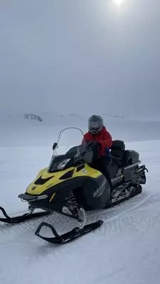 A person in cold-weather gear on a yellow and black snowmobile