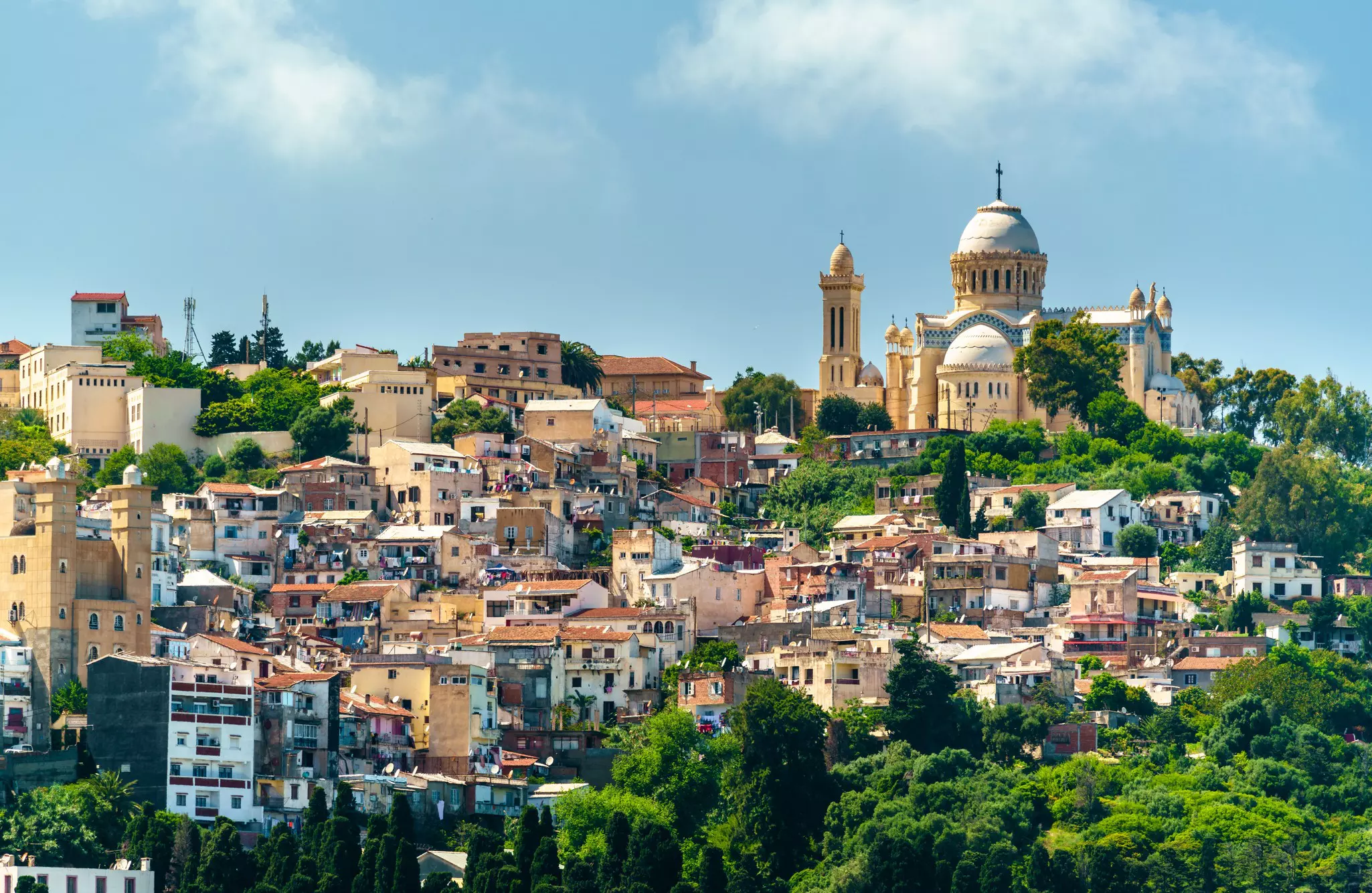 A dome-shaped church surrounded by a sloping hill covered with apartment buildings and trees.