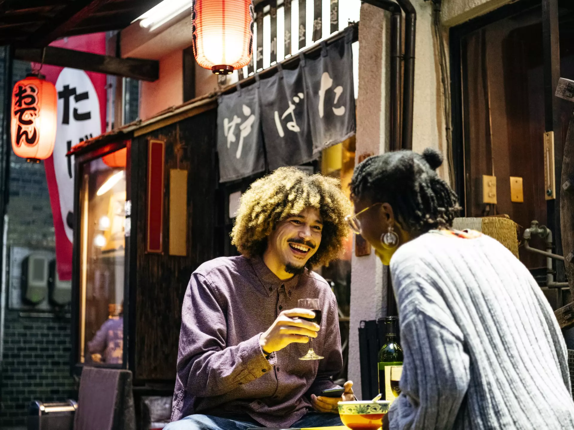 Attractive couple laughing with wine outside Japanese restaurant