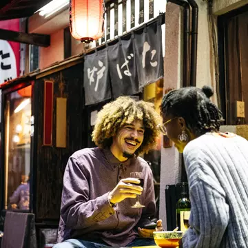 Attractive couple laughing with wine outside Japanese restaurant