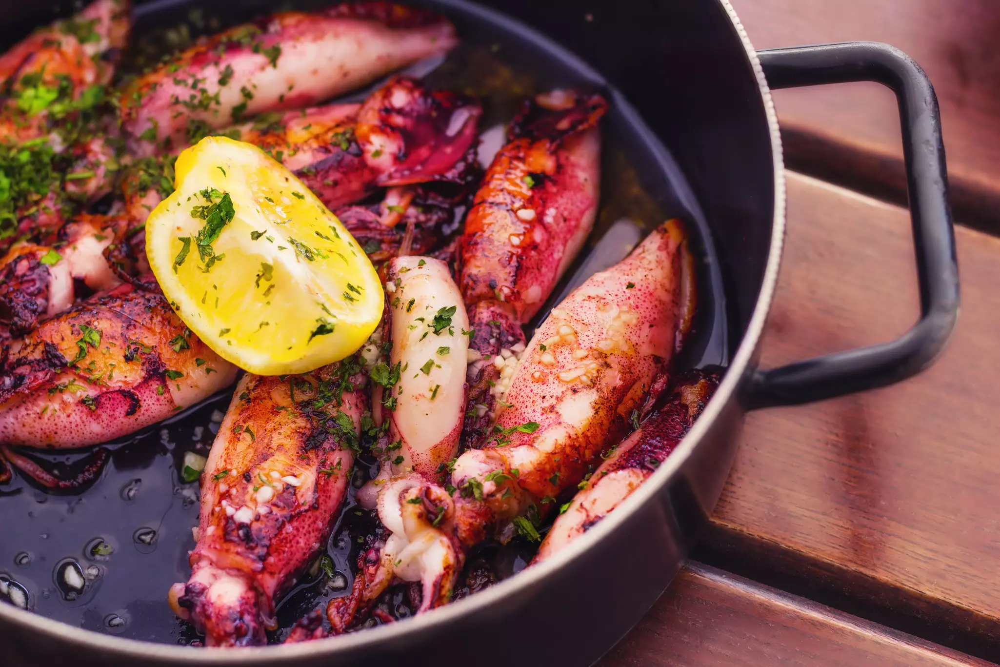 Red squid, herbs and lemon in a cast-iron dish on a table