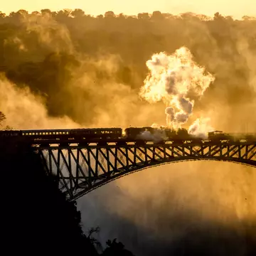Steam Train driving over Steel Bridge at Victoria Falls  License Type: media  Download Time: 2023-07-10T15:54:35.000Z  User: nic.dhoedt_lonelyplanet  Is Editorial: No  purchase_order: