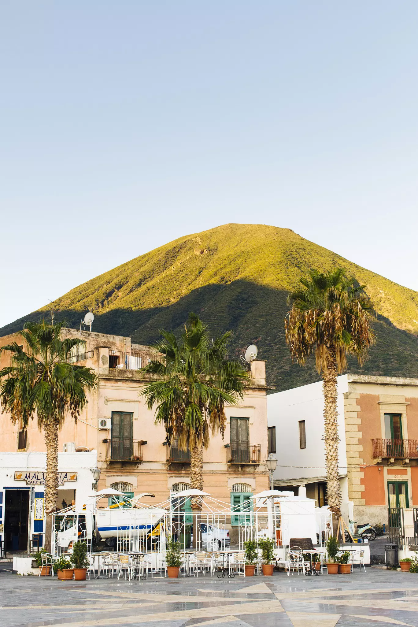 Outside a cafe on main square in Malfa, Sicily, with chairs, tables and potted plants