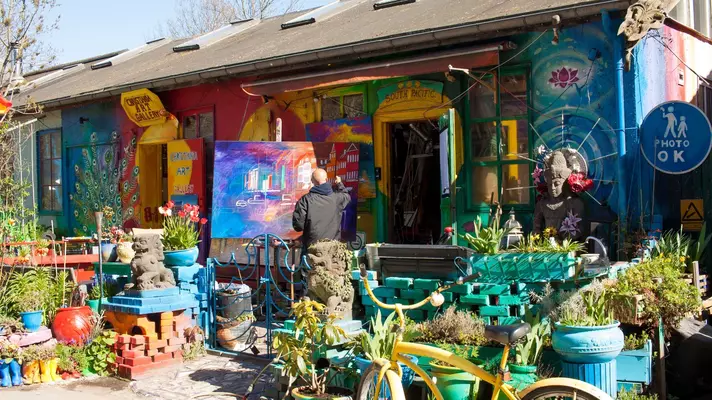 A painter outside a colorfully painted art gallery.
