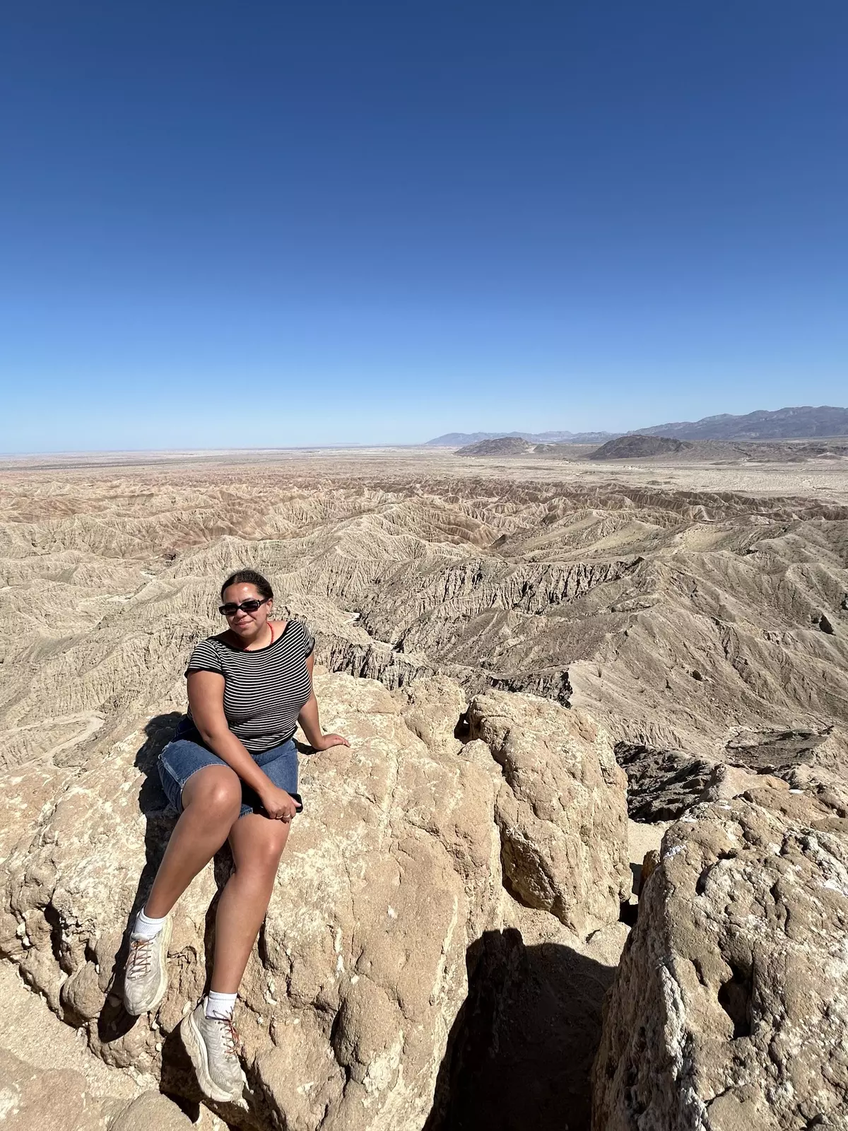 Woman sitting on rock formations under a blue sky